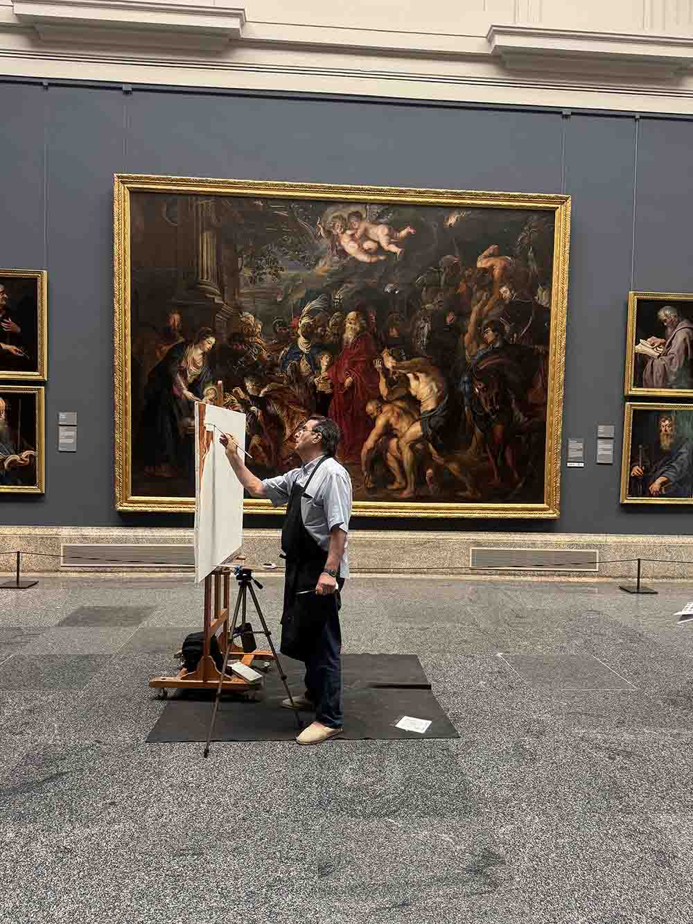 Recovered photo of an artist working at an easel in front of a large painting in a Madrid museum.